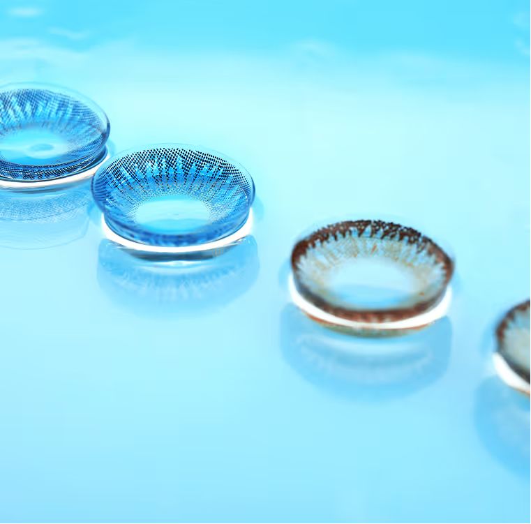 Four contact lenses in a row on a light blue surface
