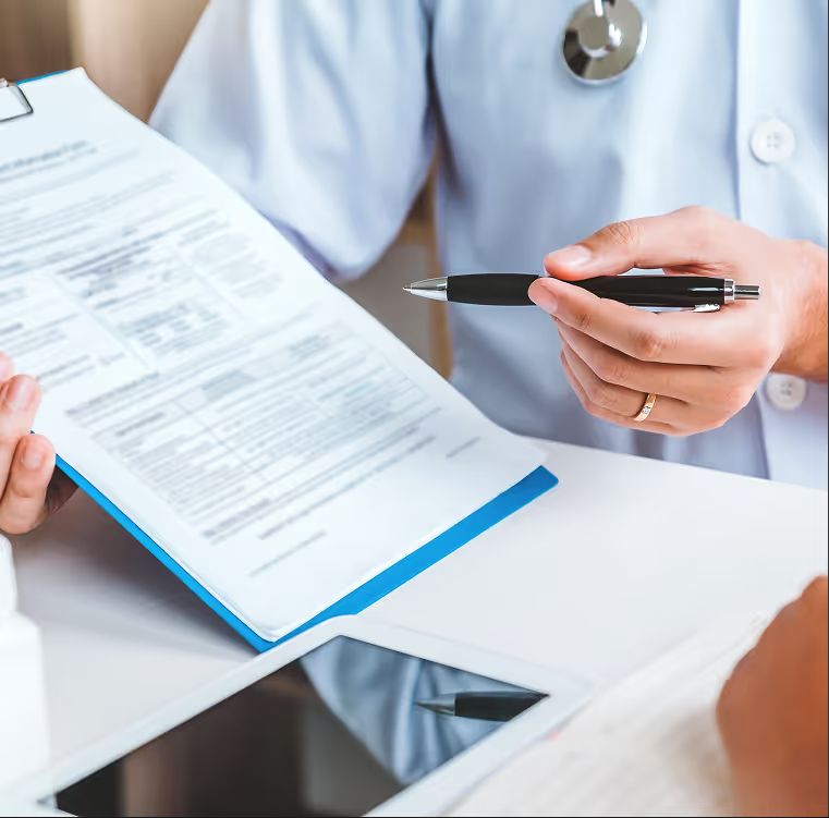 Hand holding a pen over a patient form on a clipboard